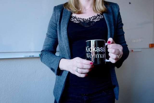 Cropped image of a woman holding a mug reading 